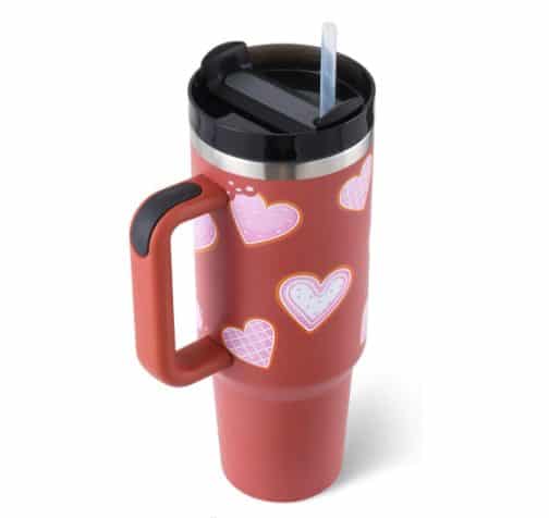 Insulated travel mug with heart patterns and straw.