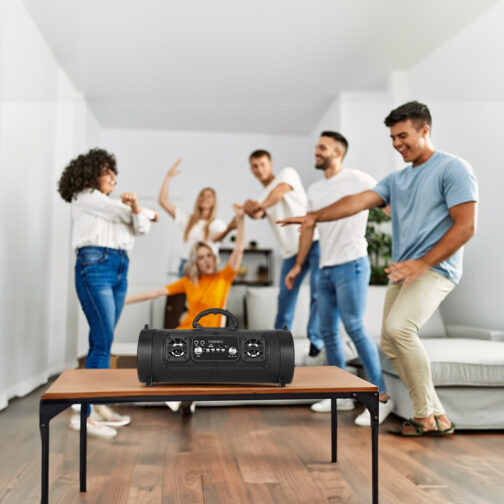 People dancing around speaker in living room.